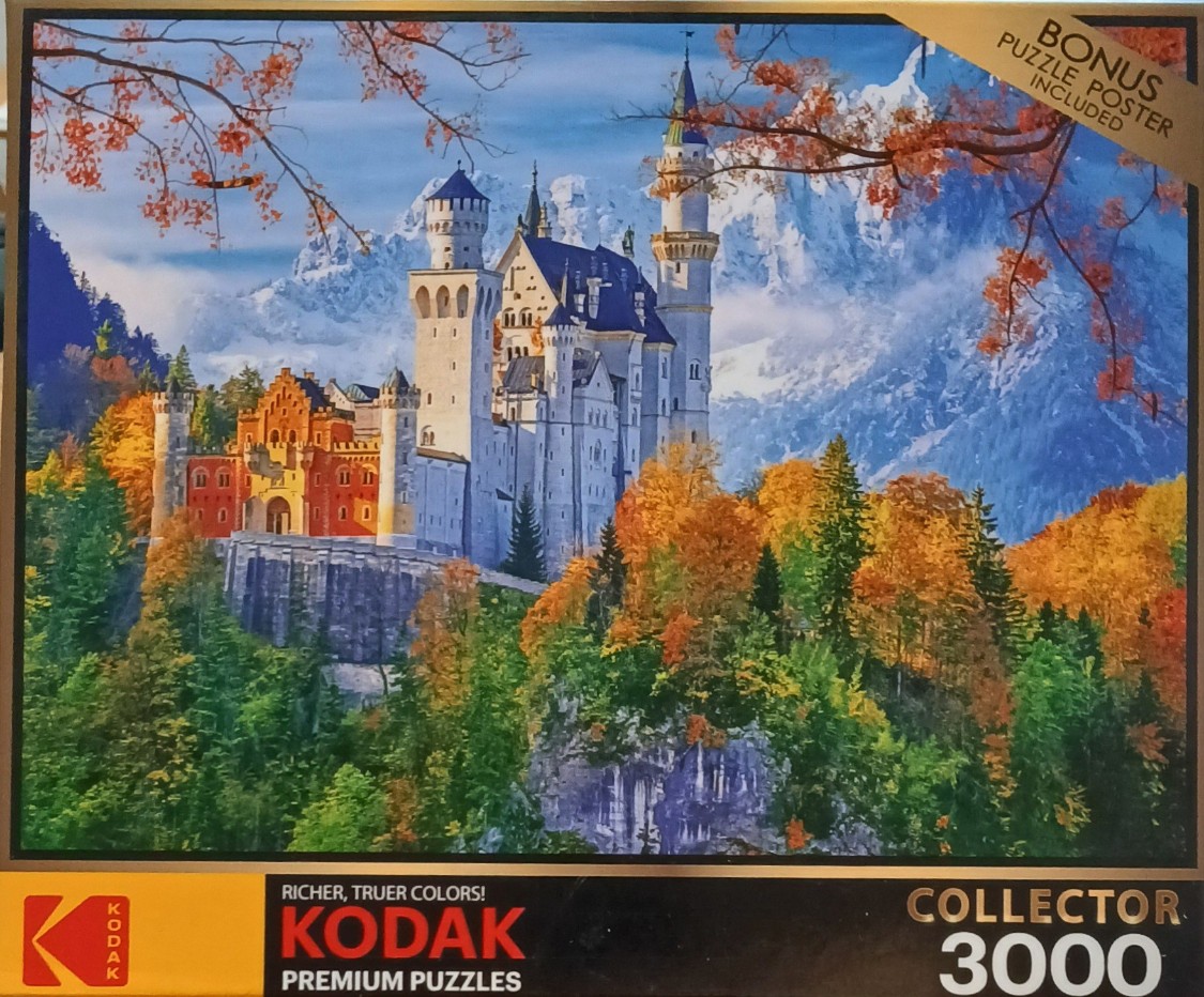 Neuschwanstein Castle surrounded by vibrant autumn trees and snow-capped mountains.