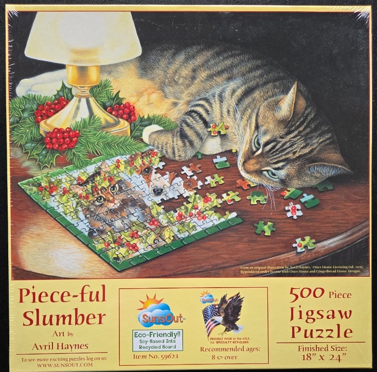 A tabby cat looking at a partially assembled puzzle of a kitten on a wooden table near a Christmas lamp.