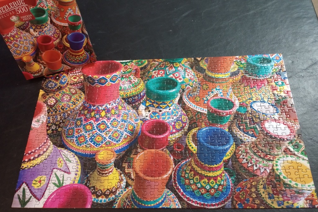A close-up view of numerous vibrant, intricately patterned ceramic vases arranged closely together.