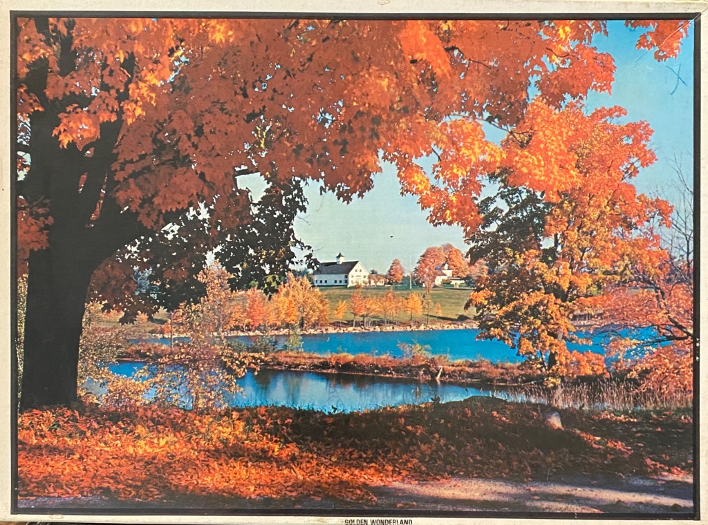 A rural landscape in autumn featuring orange maple trees, a calm blue lake, and a white farmhouse in the distance.