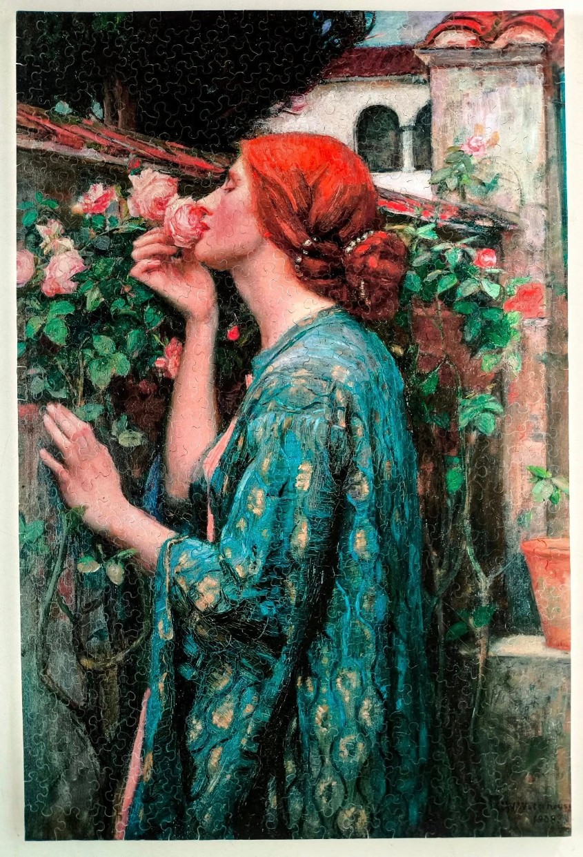 A romantic painting of a red-haired woman smelling pink roses in a garden by a stone building.