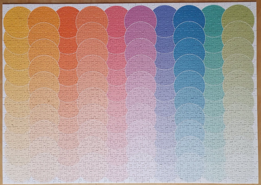 A rectangular grid of circles showing a smooth color spectrum from yellow to orange, pink, purple, blue, and green.