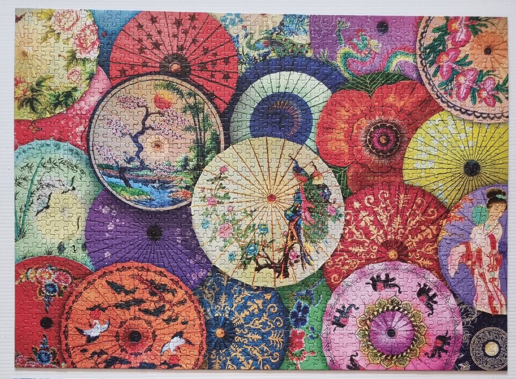 A vibrant collage of overlapping decorative parasols featuring floral, landscape, and cultural motifs.