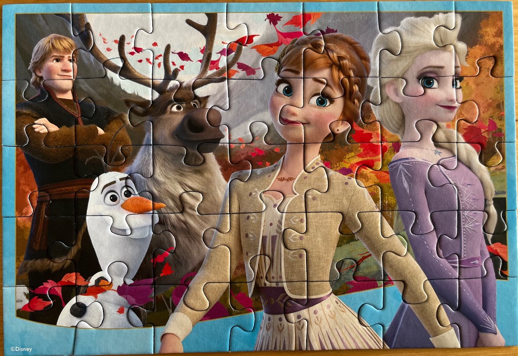 Animated characters Kristoff, Sven, Olaf, Anna, and Elsa standing in a forest with autumn leaves.