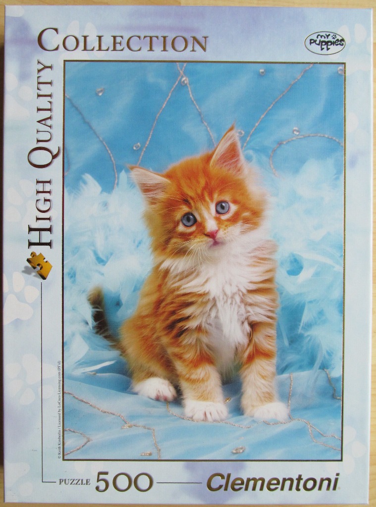 A fluffy orange and white kitten sits amidst soft blue feathers and delicate, sparkling fabric.