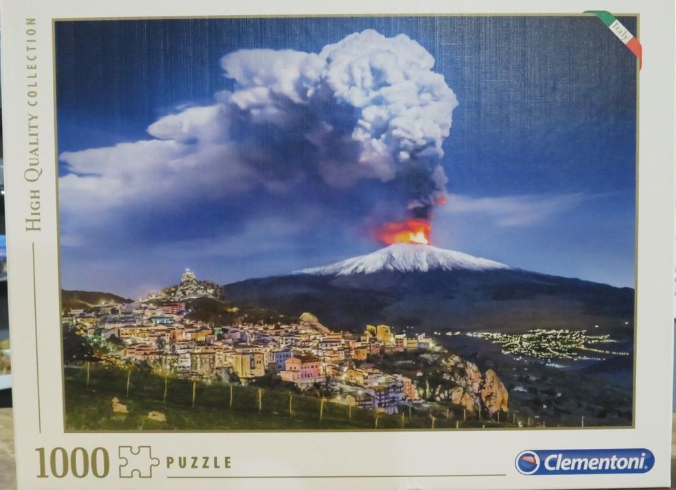 Mount Etna erupting at twilight with a lit village in the foreground