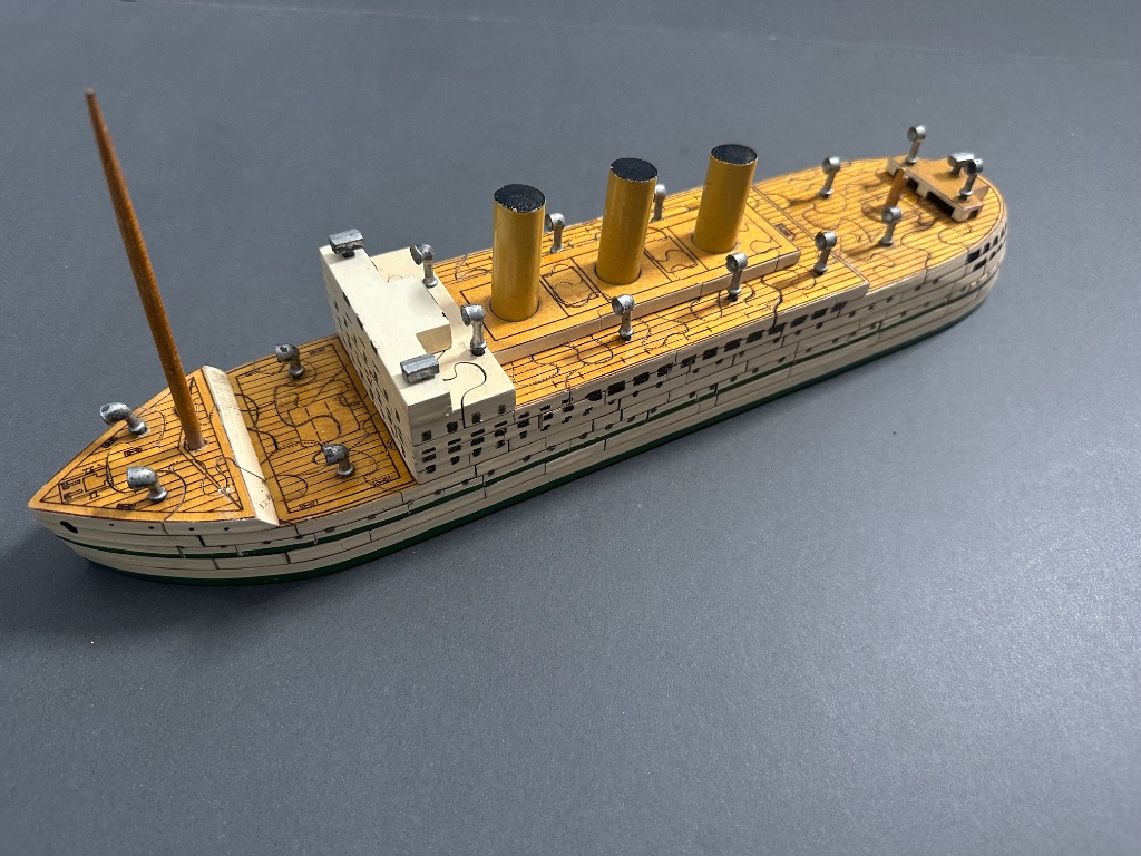 A model of the Titanic ship against a grey background.