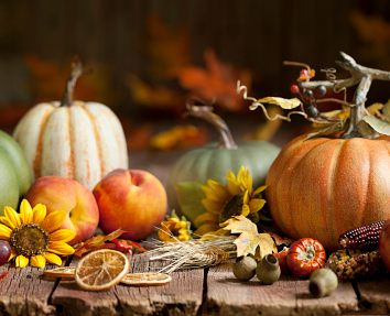 Autumn harvest still life with pumpkins, peaches, sunflowers, and dried citrus on a wooden table.