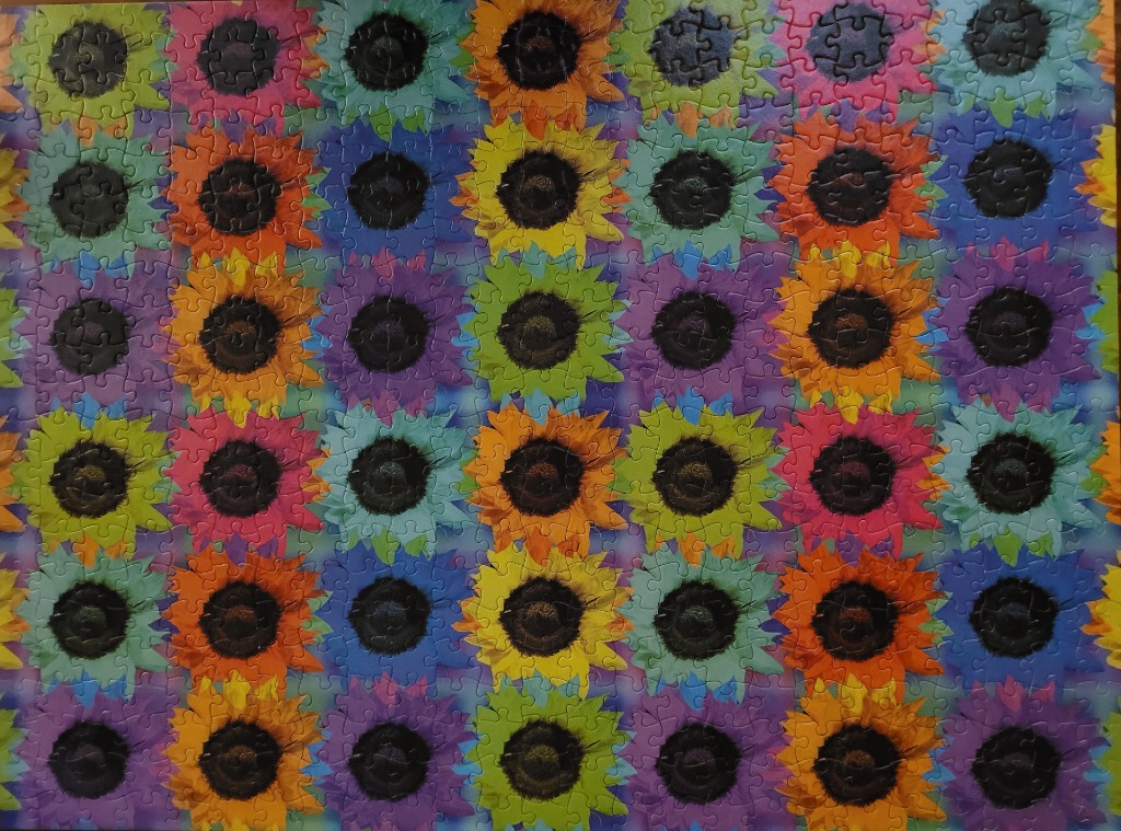 A repeating pattern of sunflowers in vibrant, non-naturalistic colors like purple, lime green, orange, and blue.