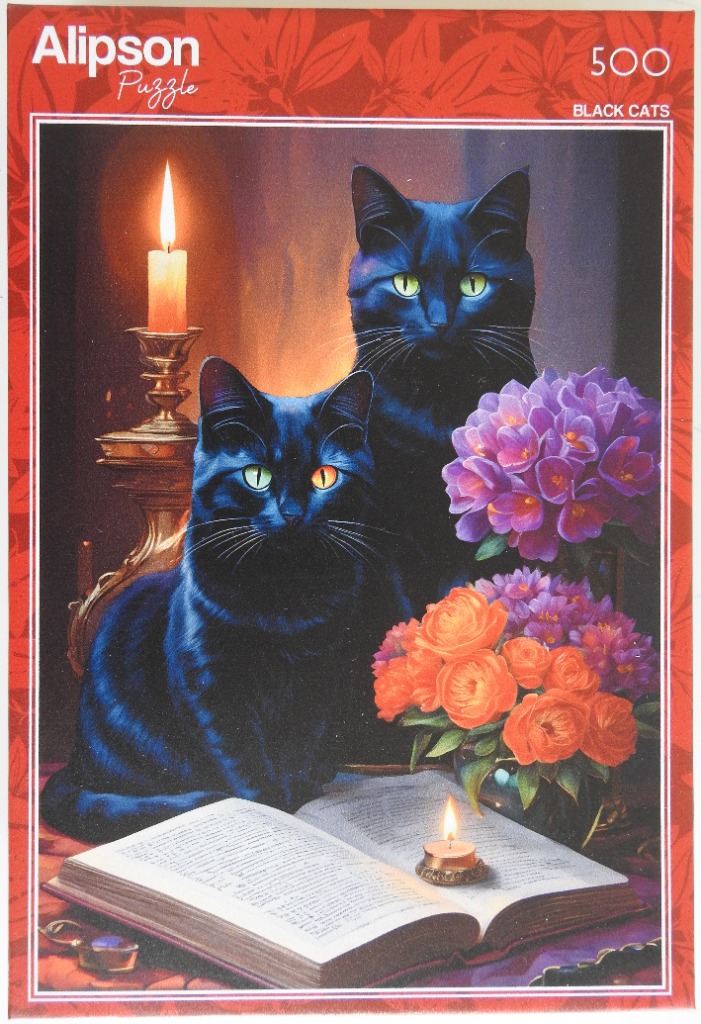 Two black cats sit near a candle and a bouquet of orange and purple flowers beside an open book.