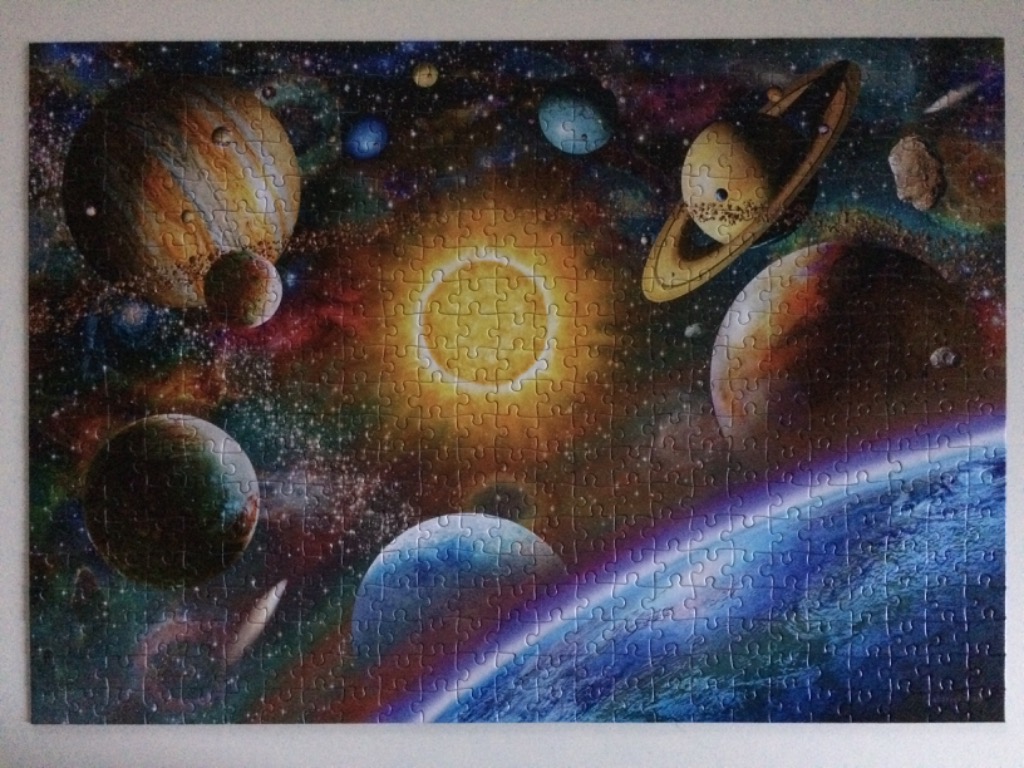 Vibrant space scene with a bright central star, various planets, and a nebula-filled galaxy background.