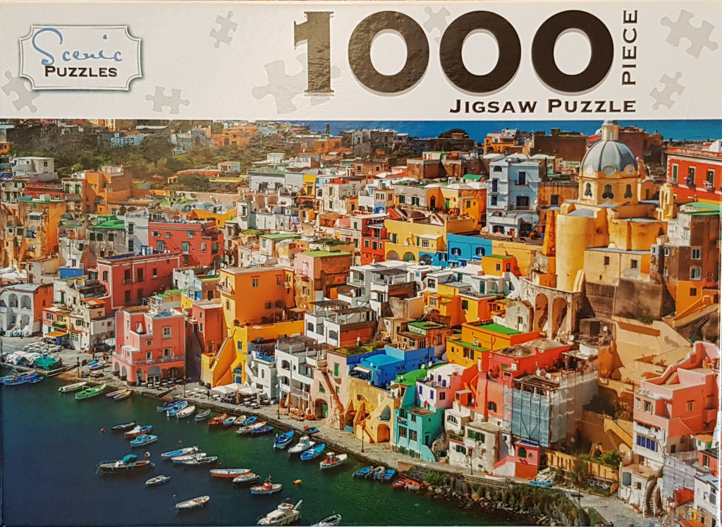 A high-angle photograph of Procida, Italy, showing colorful buildings along a harbor filled with small boats.