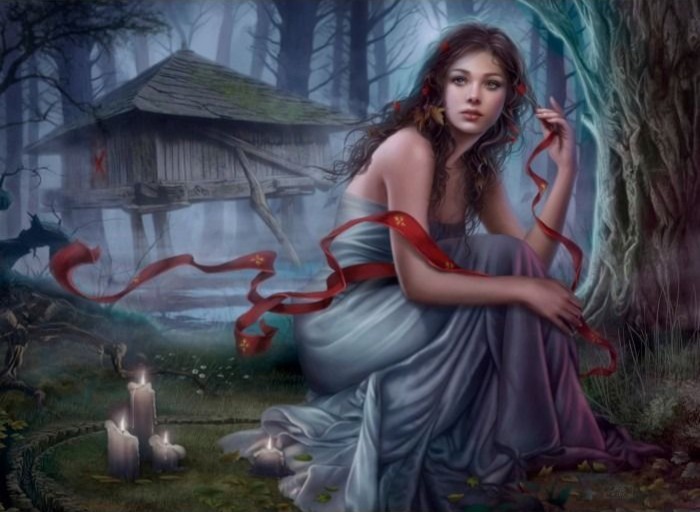 A woman in a grey dress sitting in a forest near a wooden hut, holding a long red ribbon with candles nearby.