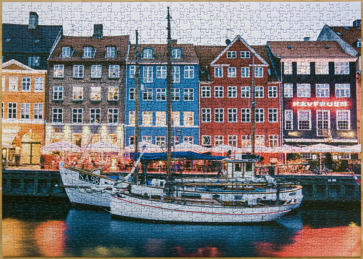A night scene in Nyhavn, Copenhagen with colorful waterfront buildings and a boat moored in the canal.