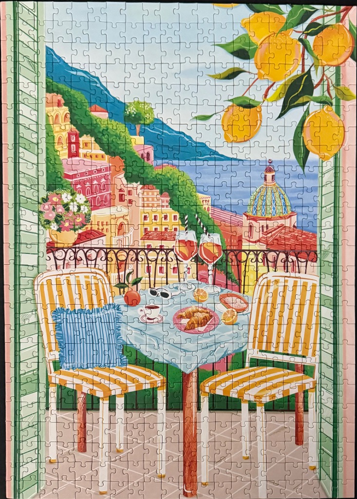 A balcony scene in Italy overlooking a coastal town with lemon branches in the foreground.