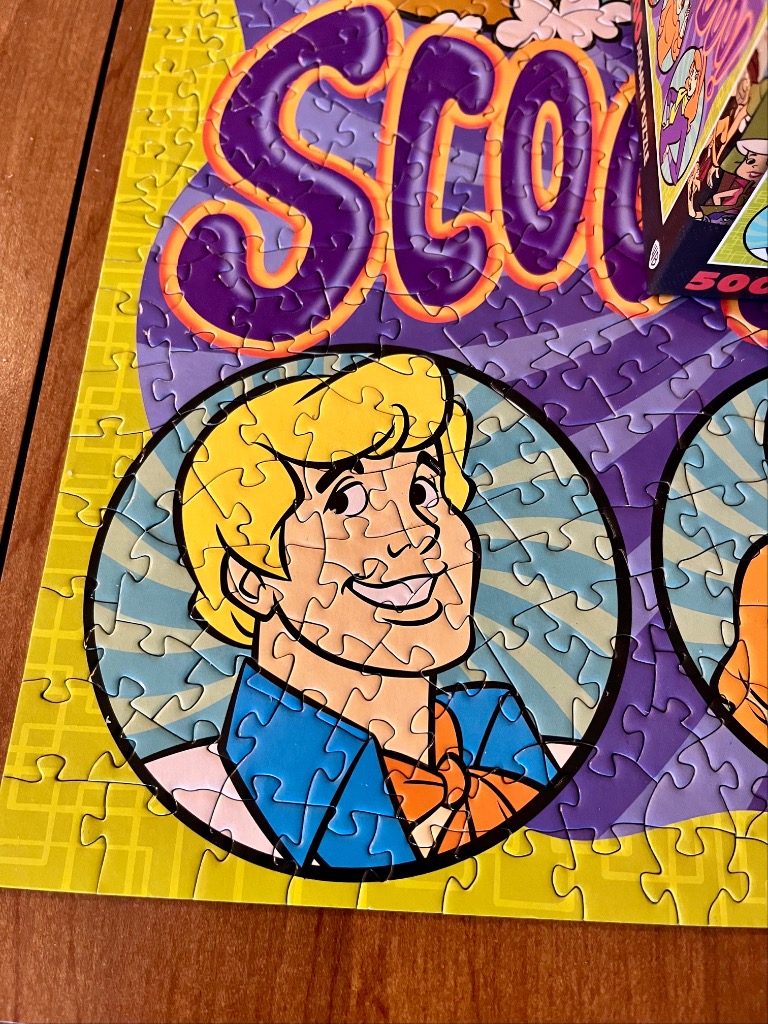 Cartoon portrait of Fred from Scooby-Doo on a bright yellow and purple background.