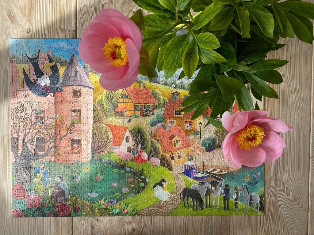 A whimsical fairytale illustration of a castle, village, and pond with characters from folklore.