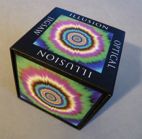 Optical illusion featuring a vibrant, multicolored radial starburst or fractal pattern.