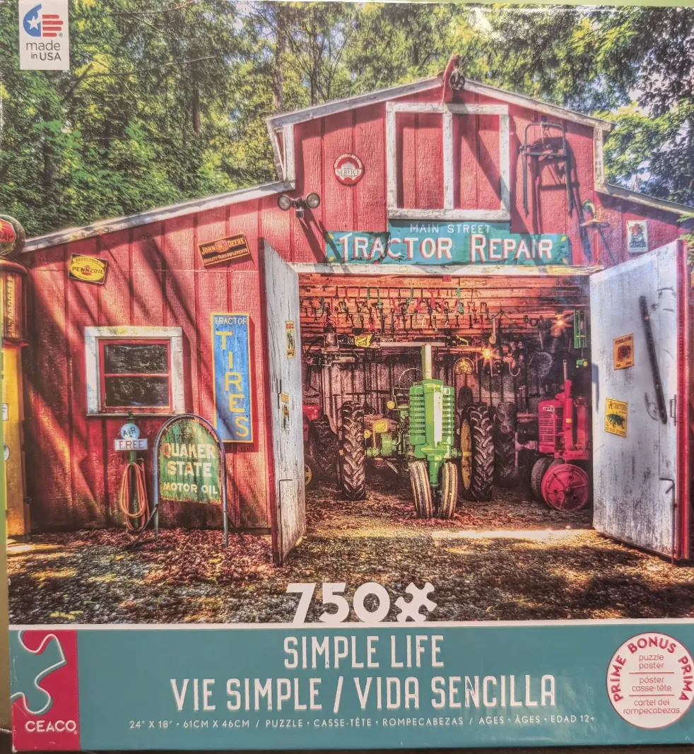 A red barn tractor repair shop with two tractors parked inside, surrounded by trees.