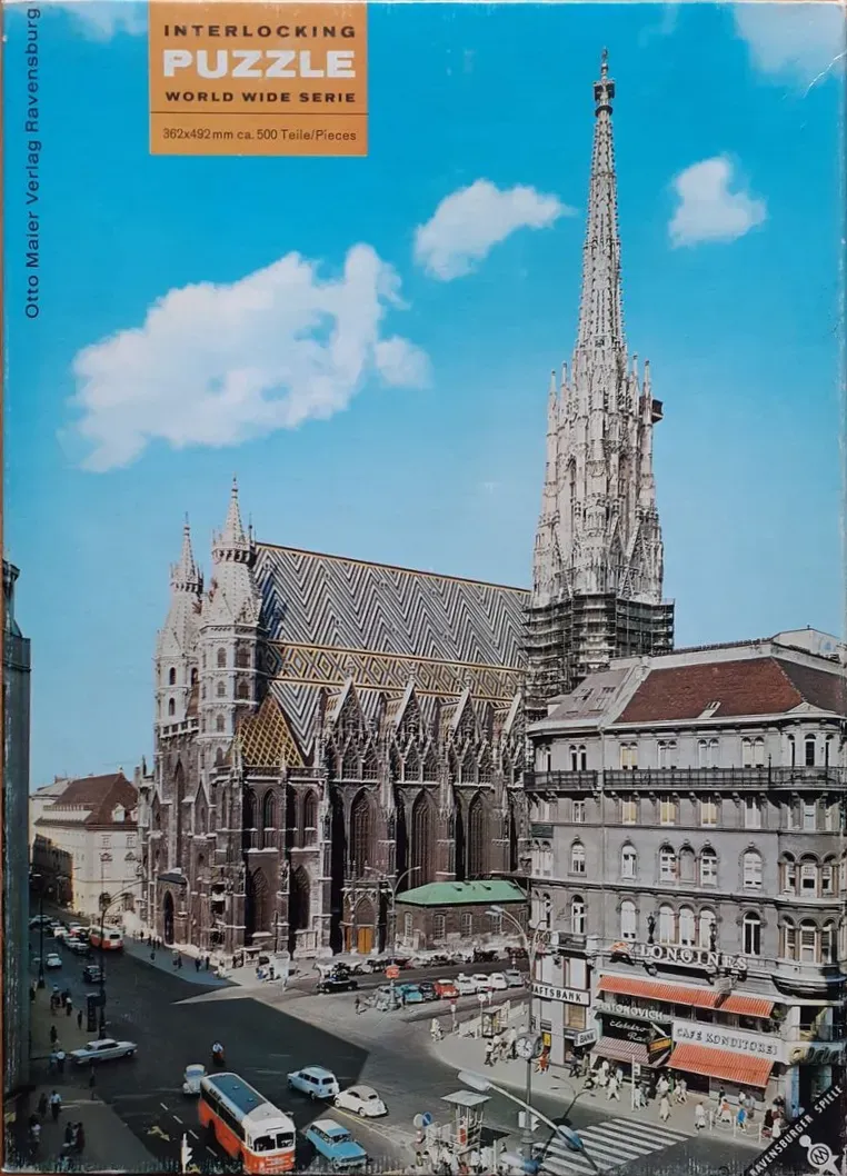 St. Stephen's Cathedral in Vienna with its iconic mosaic-tiled roof and tall spire, seen from an elevated city street view.
