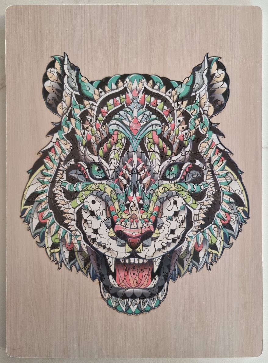A stylized illustration of a tiger face decorated with intricate, symmetrical mandala-like patterns in a vibrant color palett