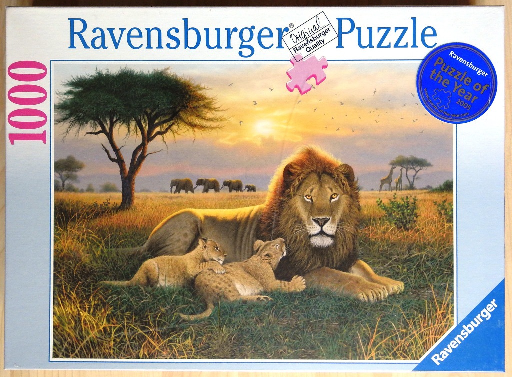 A male lion and two cubs resting in an African savanna at sunset with giraffes and elephants in the background.
