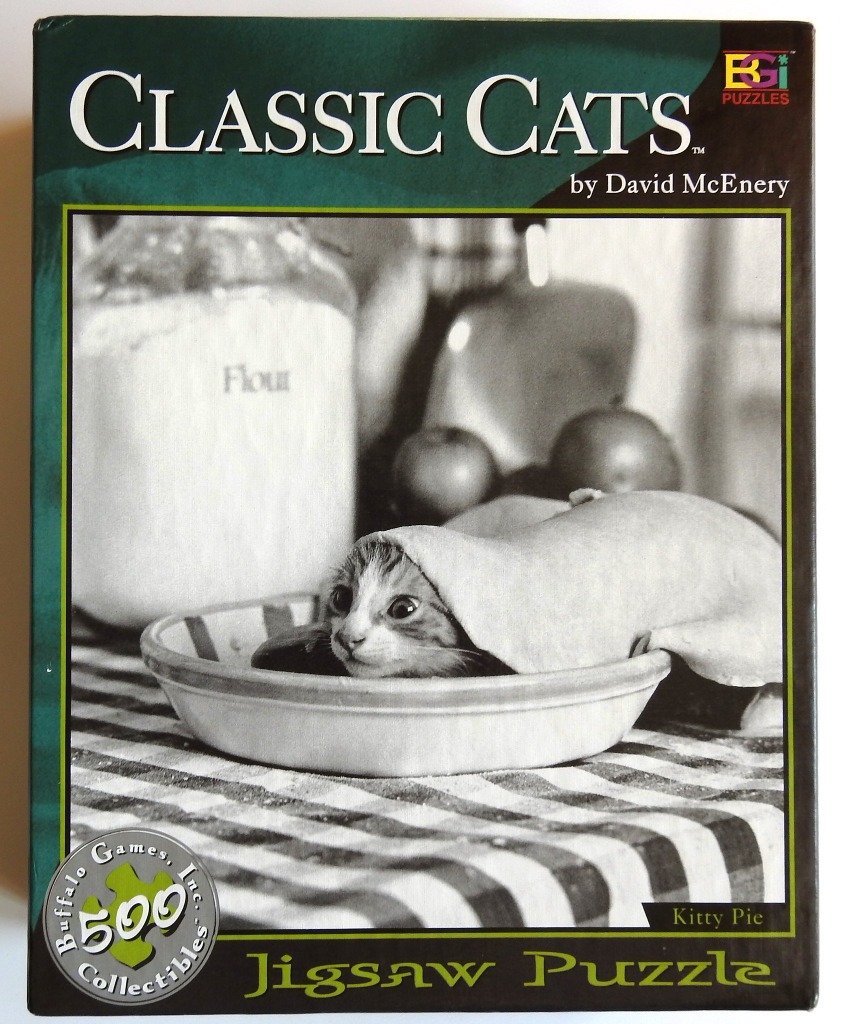A black and white photograph of a small cat sitting in a pie dish covered by a layer of pie crust.