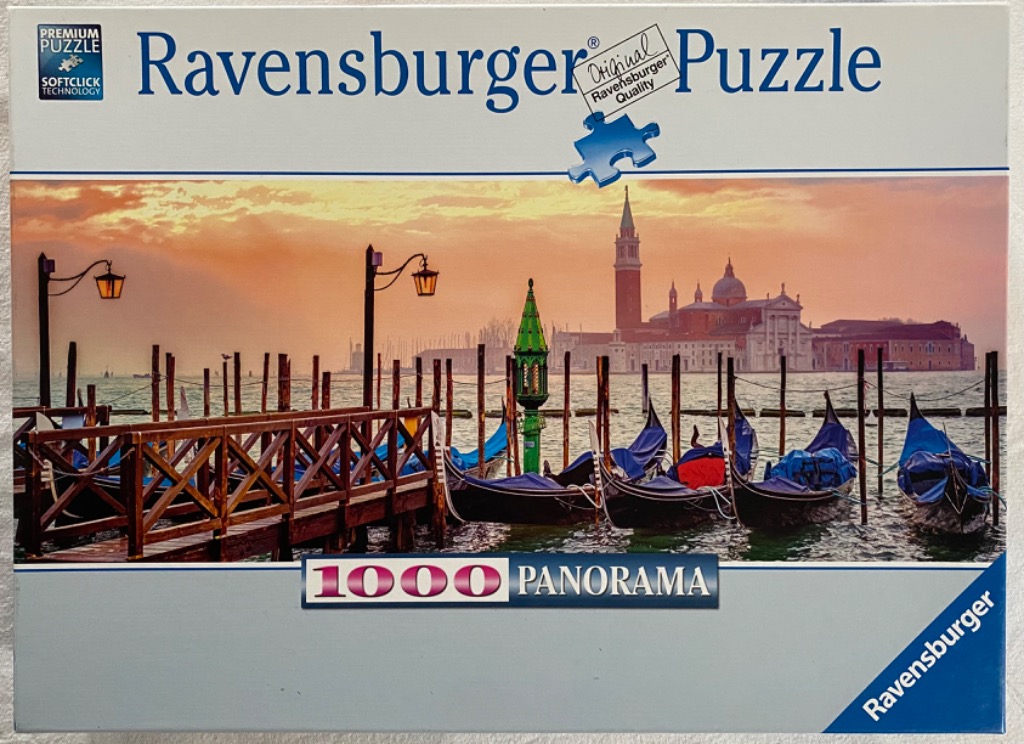 A scenic panoramic photograph of gondolas moored in Venice at sunset with the San Giorgio Maggiore church in the background.