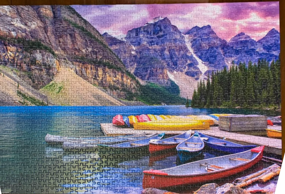 Vibrant landscape of Moraine Lake featuring a wooden dock with colourful canoes against a backdrop of mountain peaks.