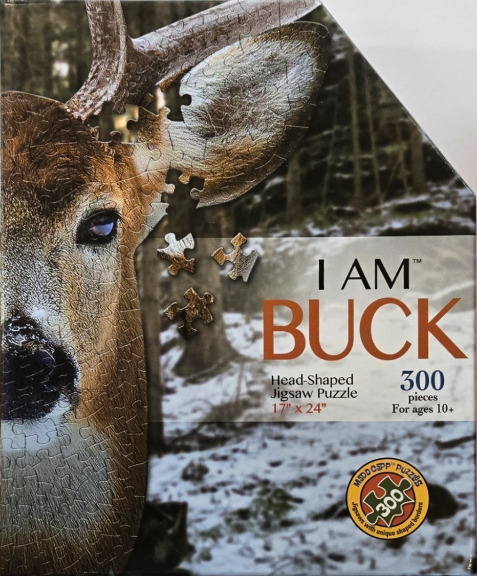 Close-up portrait of a buck in a snowy forest setting.