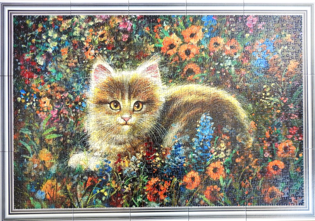 A fluffy tabby kitten sitting in a vibrant, impressionistic garden of colourful wildflowers.