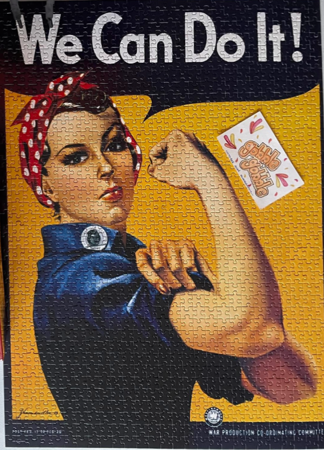 The iconic Rosie the Riveter poster featuring a woman flexing her bicep in a blue shirt and red polka-dot headband.