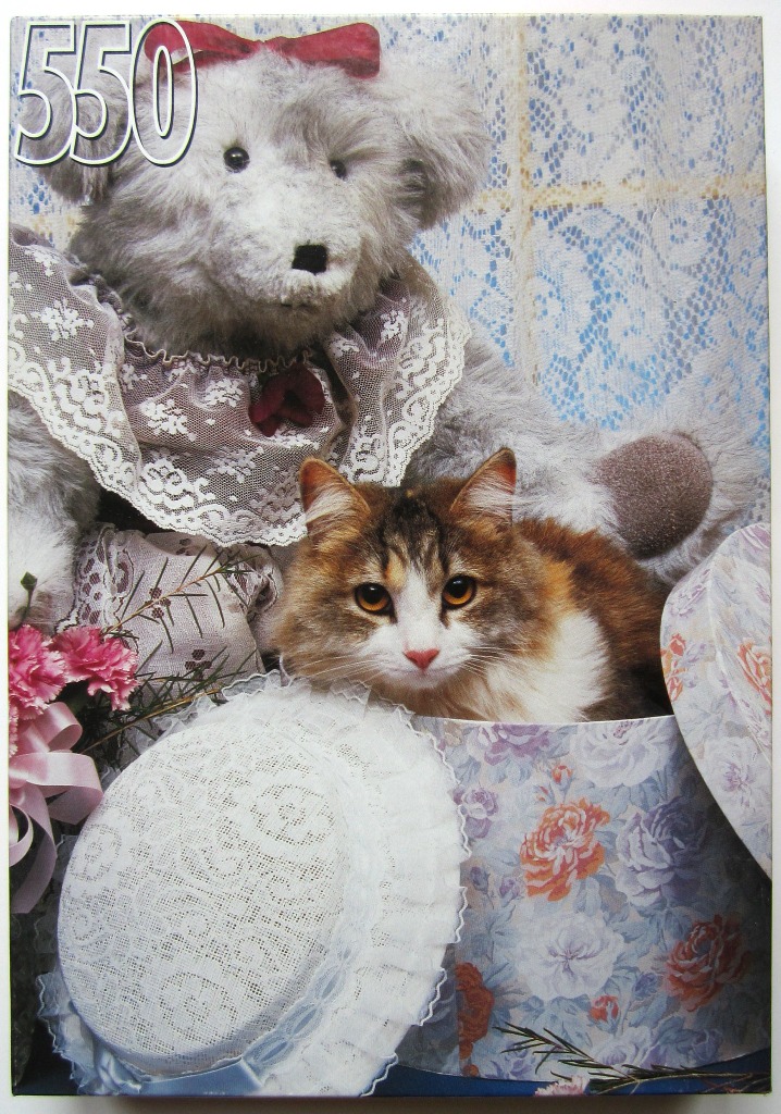 A fluffy teddy bear wearing a lace collar and a calico cat sitting in a floral hat box.