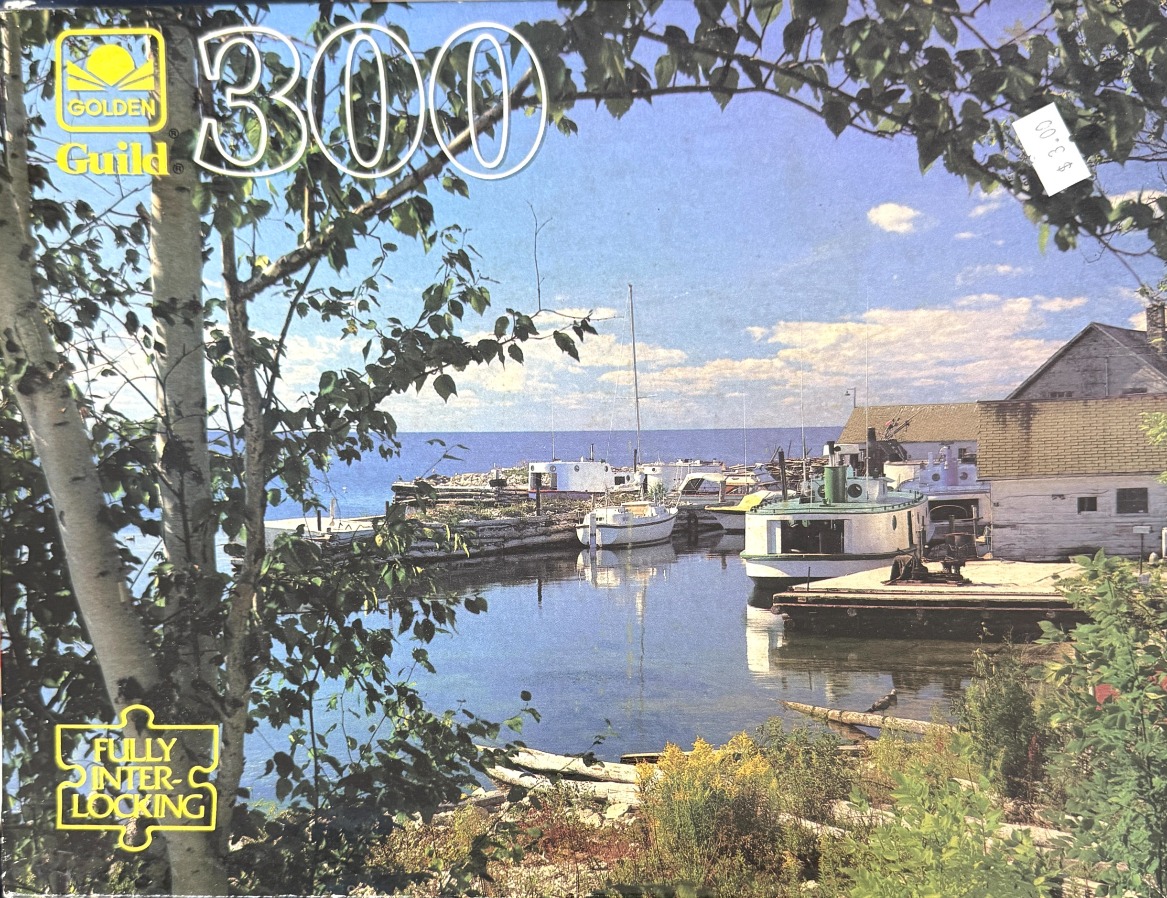 A peaceful lakeside harbor with white boats docked near weathered buildings, framed by birch trees.