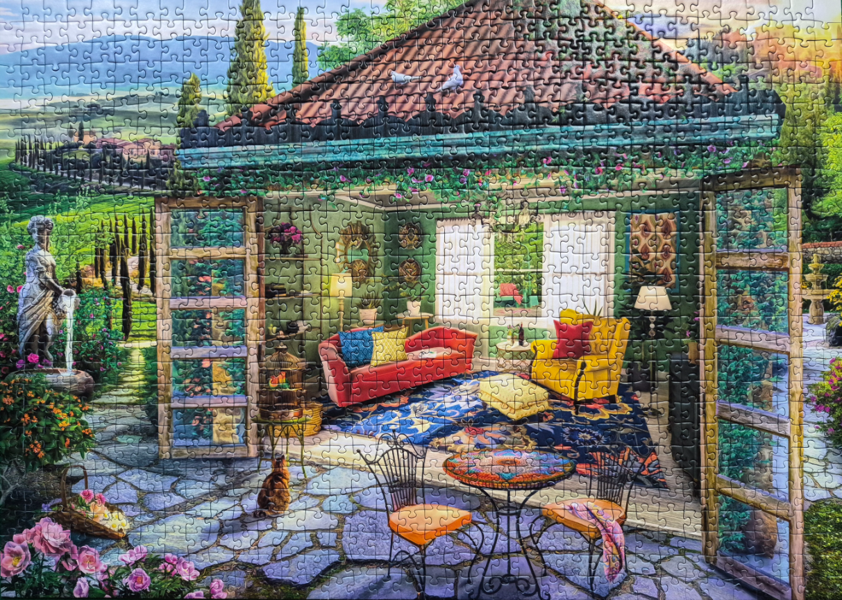 A cozy sunroom opening onto a stone patio with views of a lush Tuscan landscape.