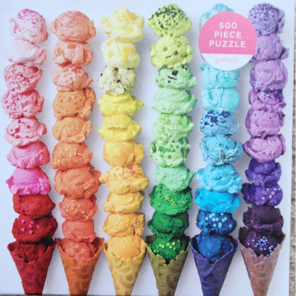 Six tall ice cream cones arranged in a rainbow spectrum against a white background.