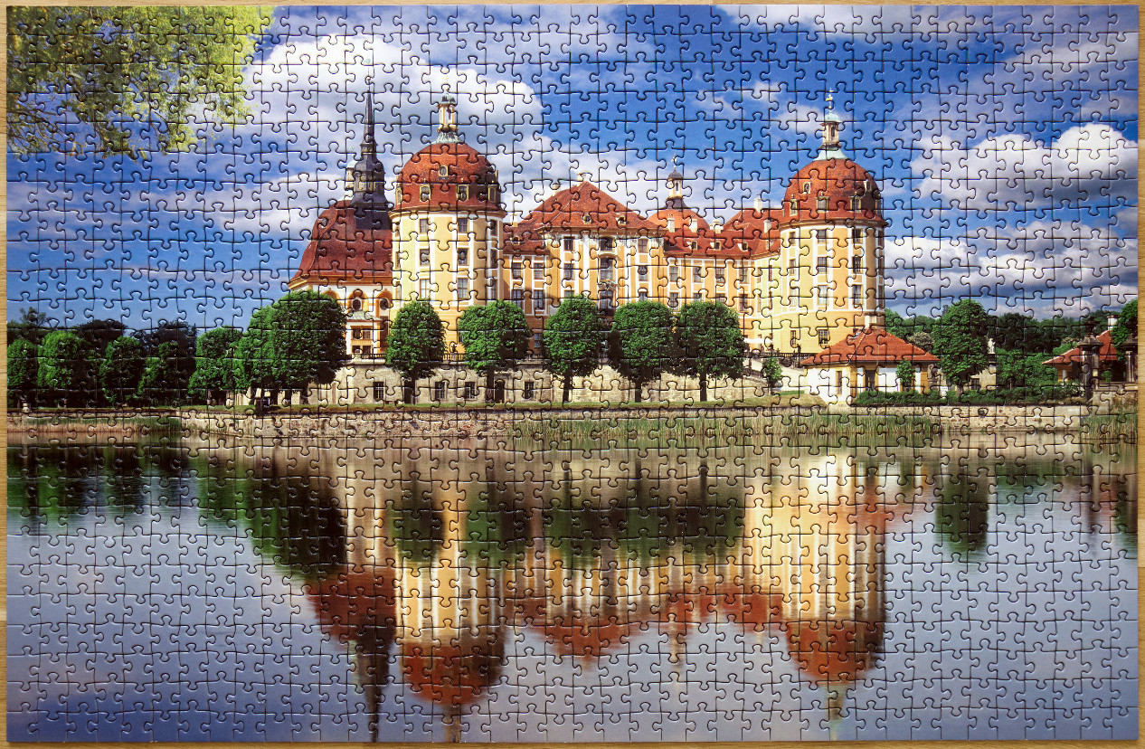 Moritzburg Castle reflected in a calm lake under a bright blue sky