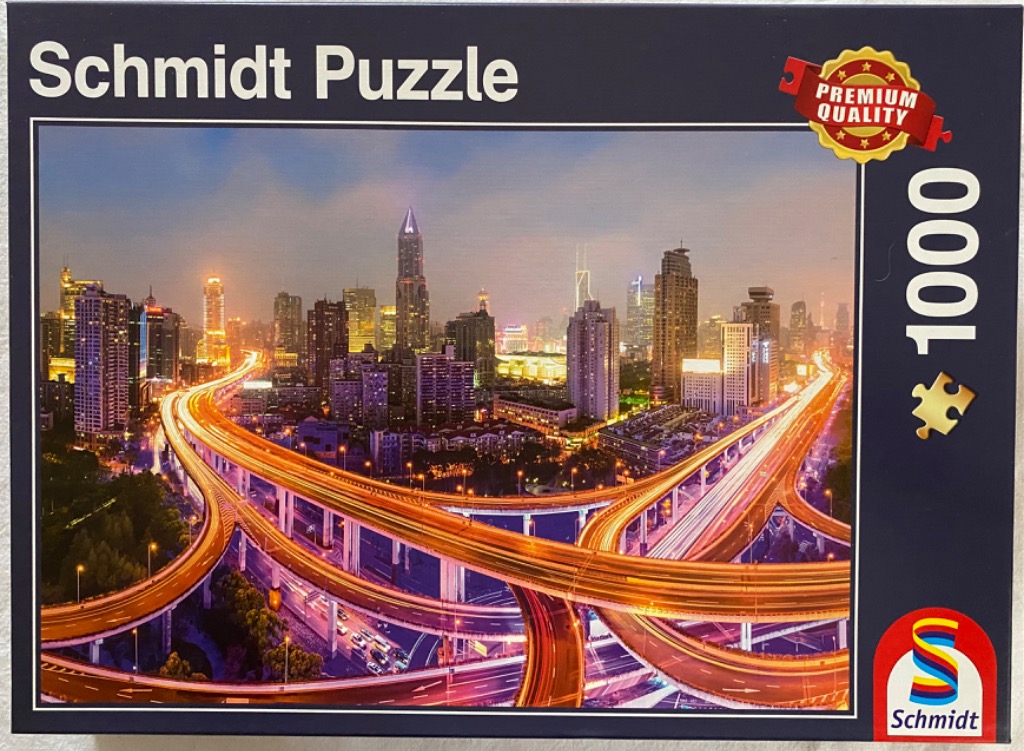A panoramic night-time view of a sprawling urban skyline featuring illuminated elevated highways.