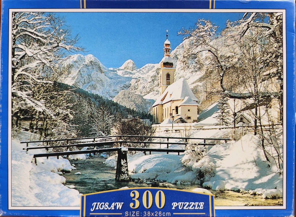 A winter landscape featuring a church near a stream, mountains, and snow-covered trees.