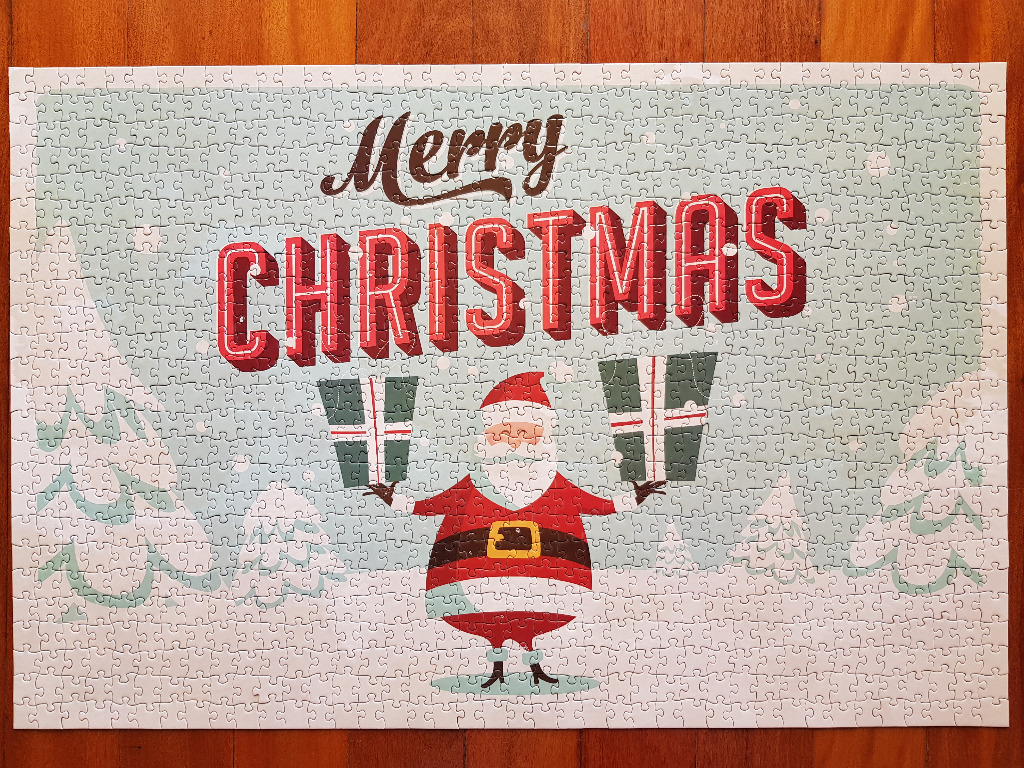A festive illustration of Santa Claus holding gifts under the text Merry Christmas against a snowy landscape.
