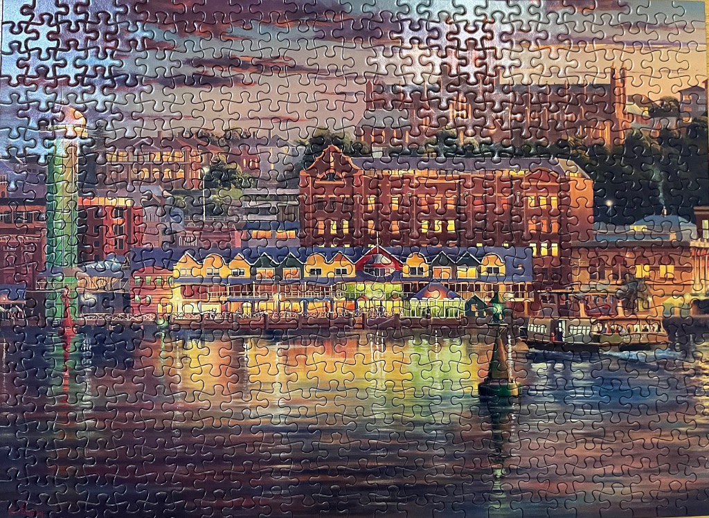 Evening view of a waterfront cityscape with historic brick buildings reflected in water.