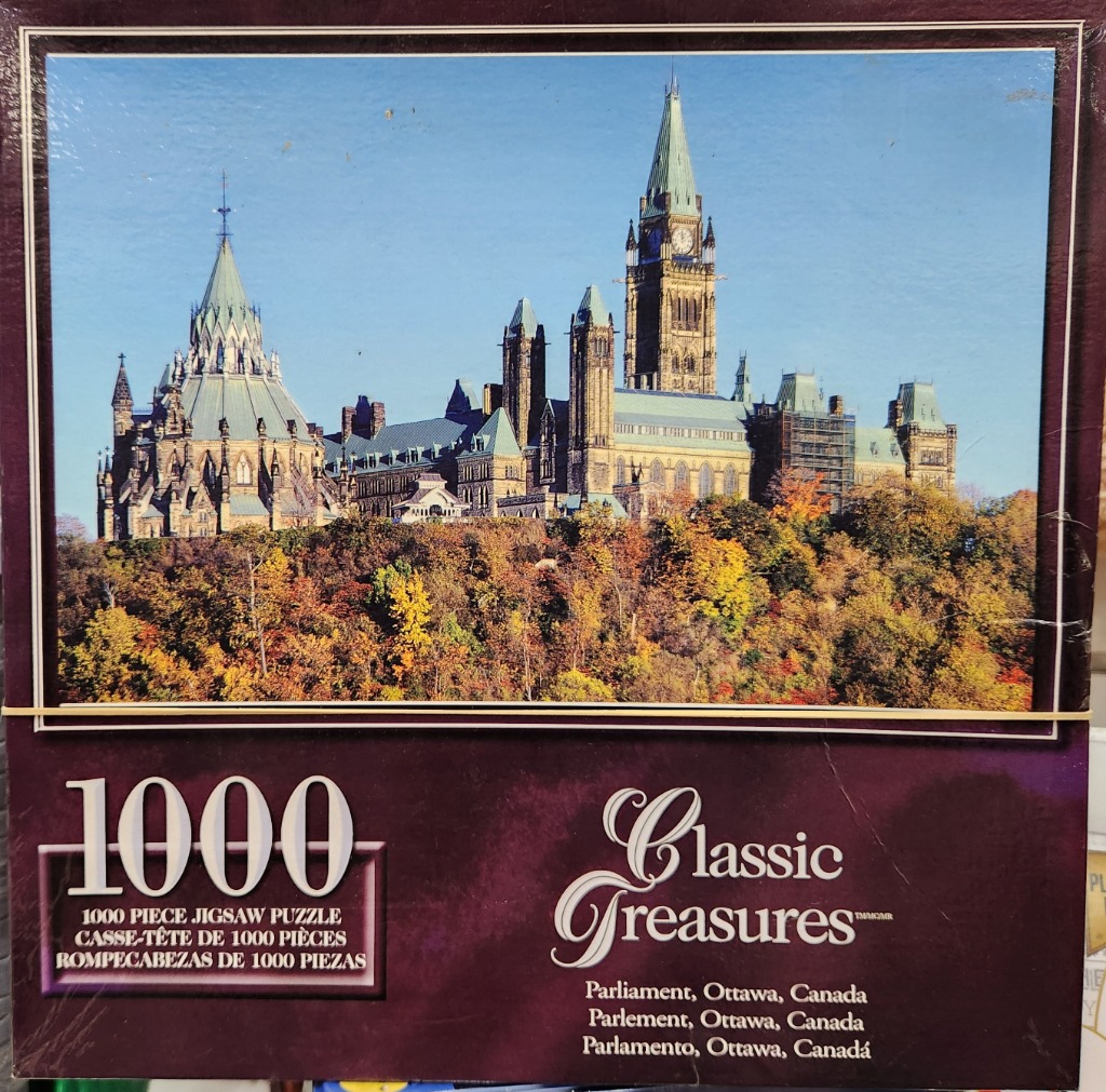 The Canadian Parliament buildings in Ottawa surrounded by autumn trees under a clear blue sky.