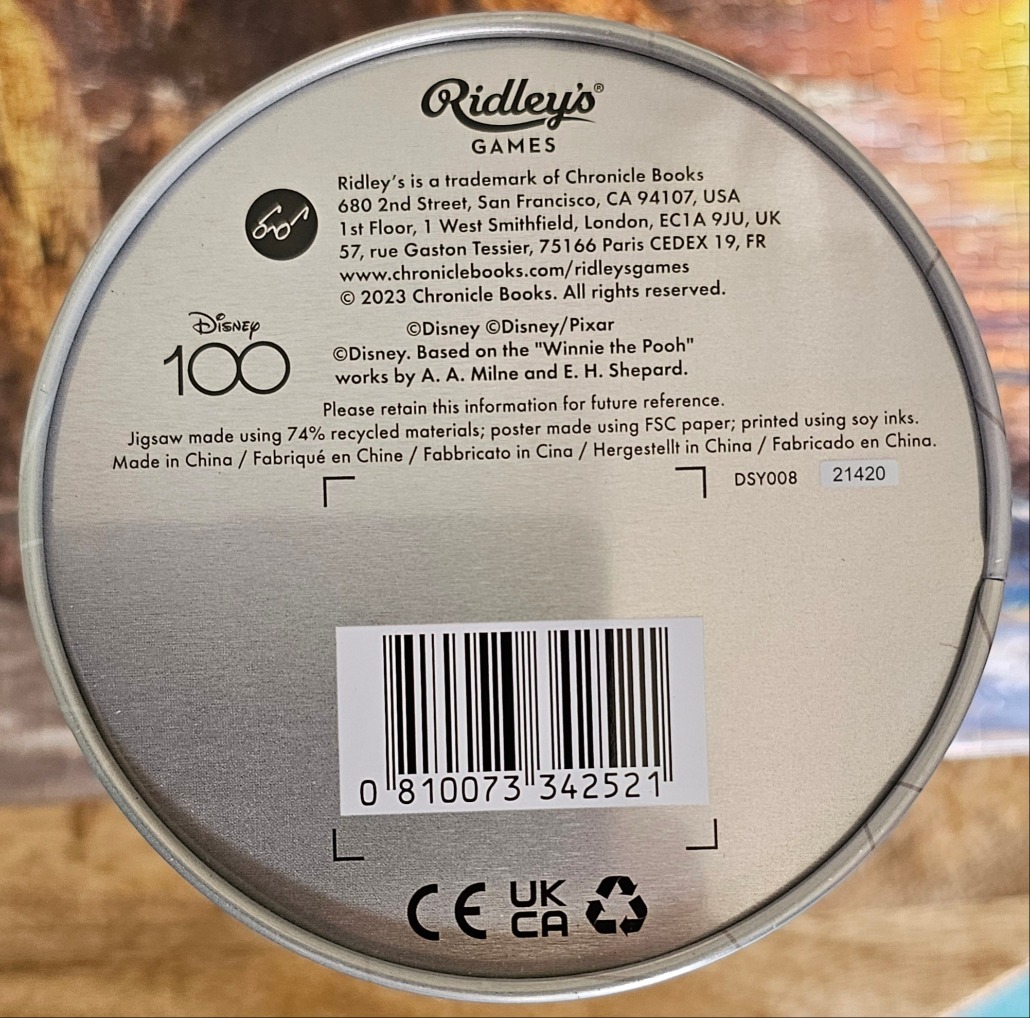 Circular product label with technical text and a barcode against a metallic silver background.