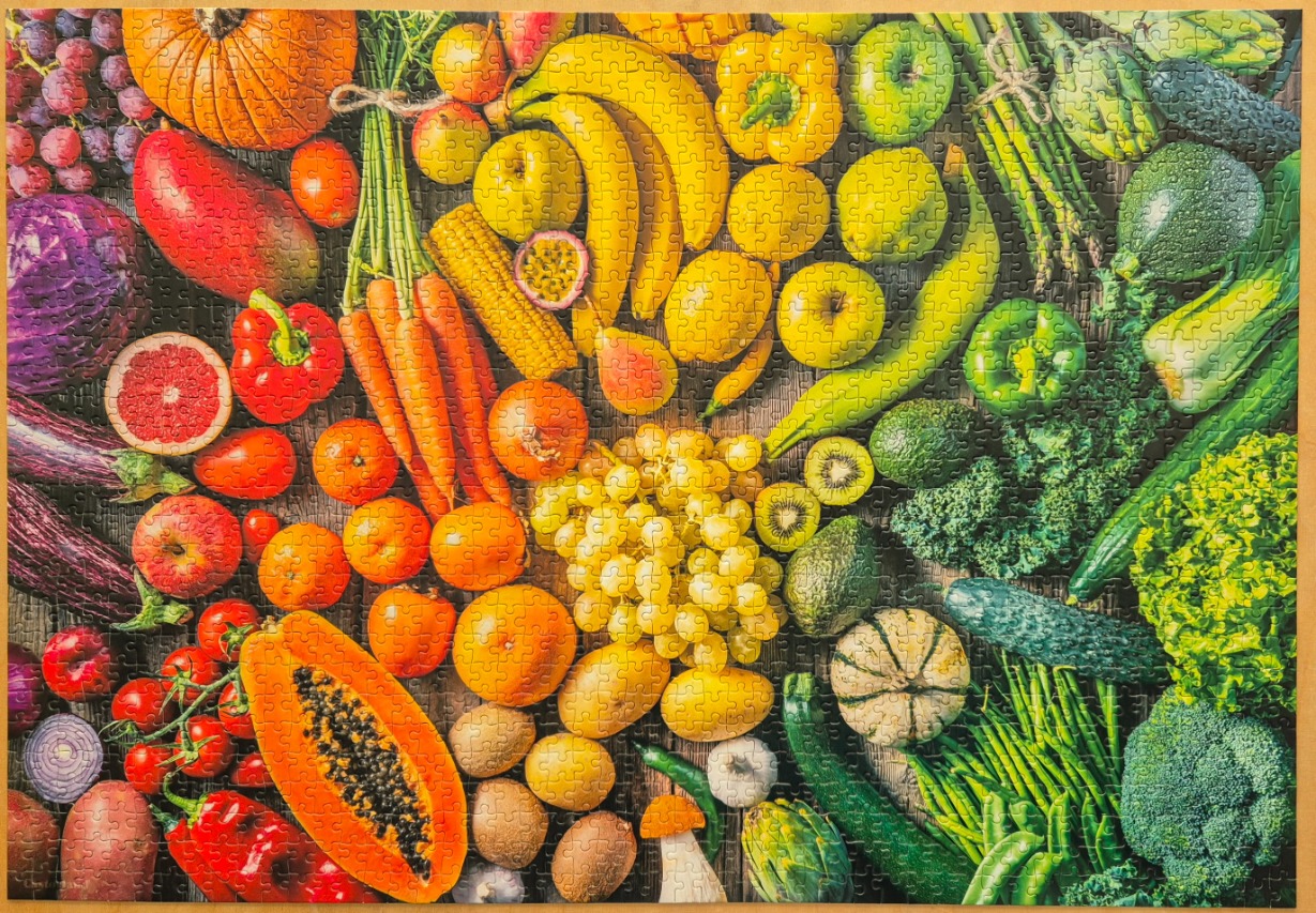 A flat-lay photograph of a vibrant assortment of fresh fruits and vegetables arranged by color.