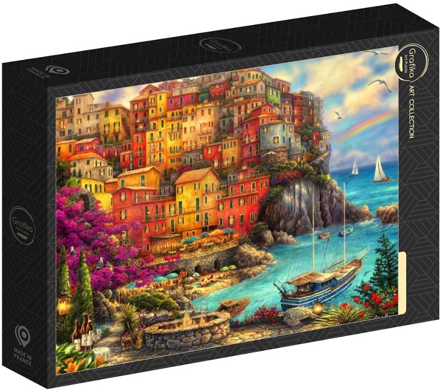Coastal village with multi-colored buildings on a cliff overlooking a blue harbor with boats at sunset