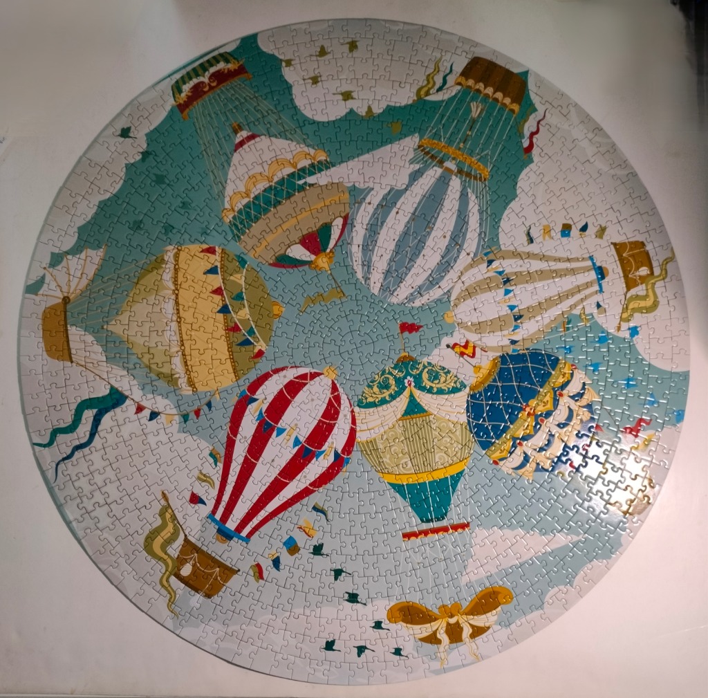 A circular illustration of six ornate hot air balloons floating in a teal sky with white clouds.
