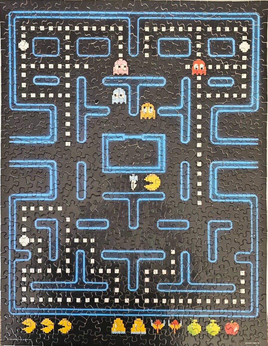A retro 8-bit video game screen featuring Pac-Man, ghosts, and a dark blue neon maze.