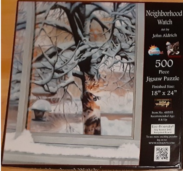 A tabby cat peering through a snow-covered window at a tree in winter.
