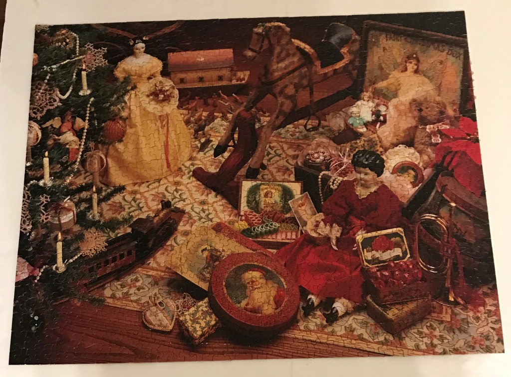 A nostalgic Christmas scene featuring antique dolls, a rocking horse, and various toys arranged on a floral rug.