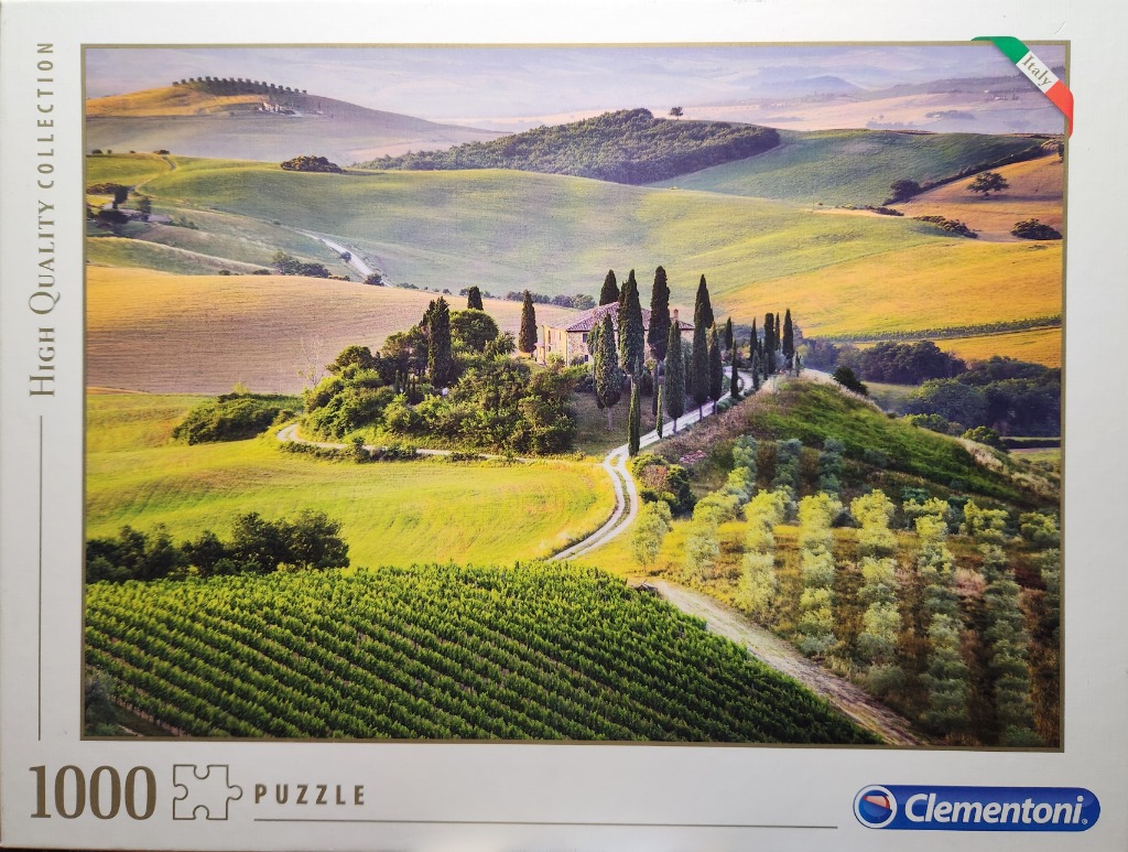 A panoramic landscape of rolling hills in Tuscany, Italy, with a stone farmhouse surrounded by tall cypress trees.